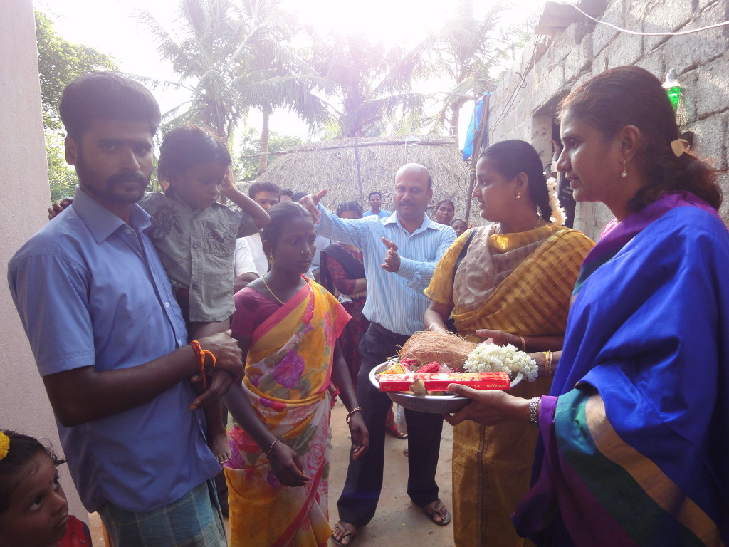 The trustee of Sriram Charitable Trust handed over a new house key to the beneficiary at Konjumangalam flood-affected area